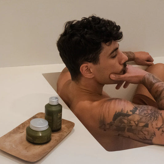 Man sitting in a bathtub with Apo.Ge jars next to him