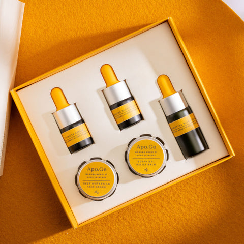 Set of Apo.Ge skincare products in a box with yellow and black packaging on an orange background