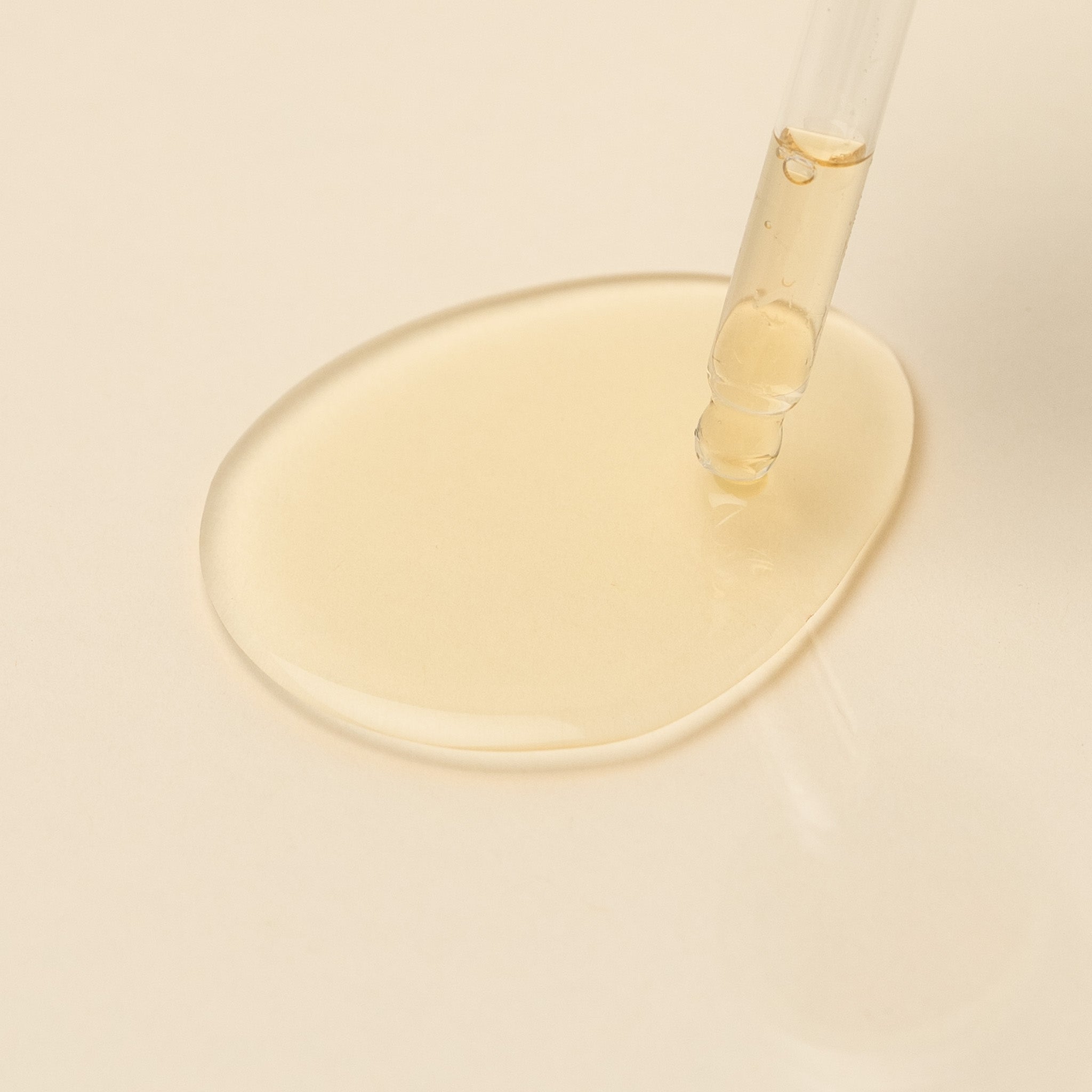 Close-up of a dropper with Apo.Ge Vitality Serum on a beige background
