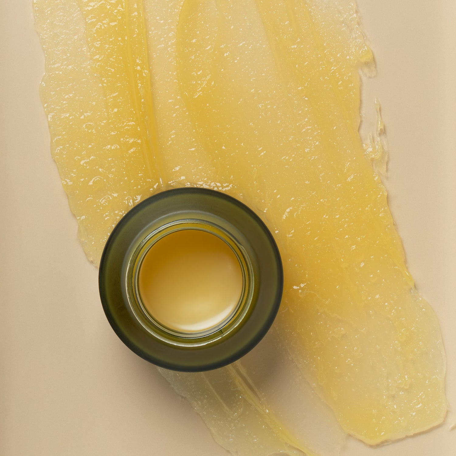 Close-up of 100ml glass jar of apo get manuka honey skincare botanical relief balm liquid next to a swipe of product texture as background