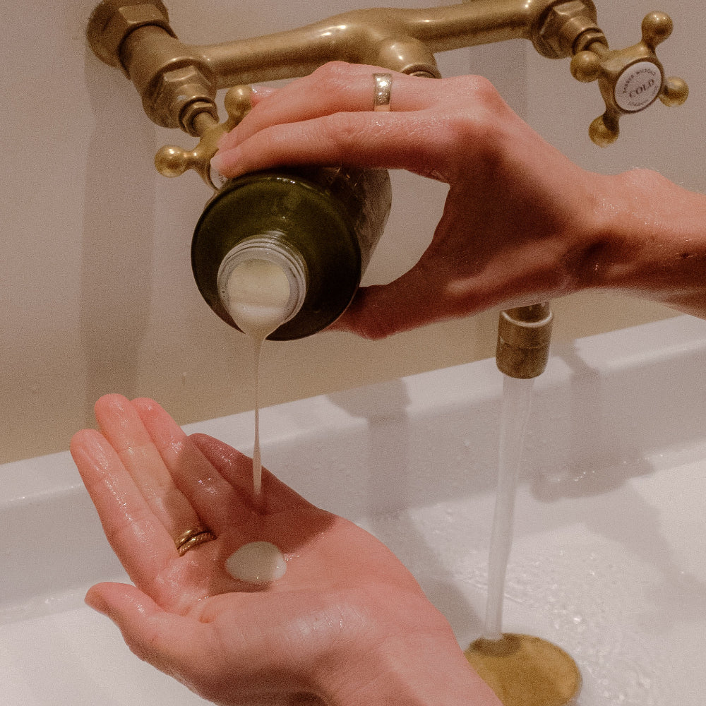 Apo.Ge clarifying milk cleanse being poured into hand over sink