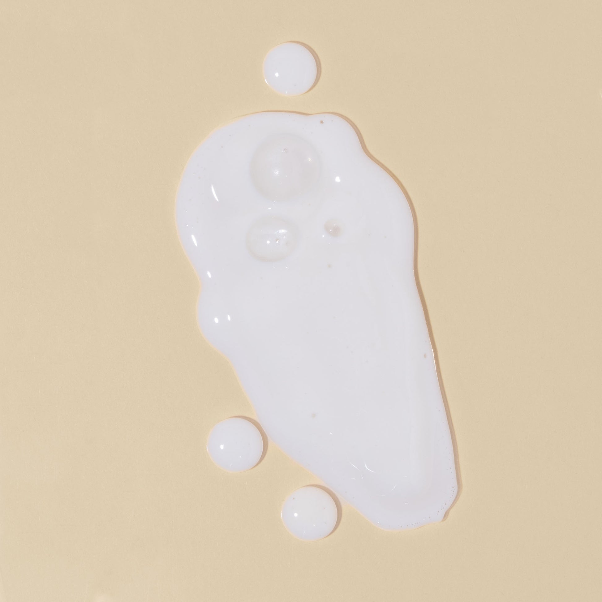 apo ge manuka honey skincare clarifying milk cleanse droplets and smears on a beige background