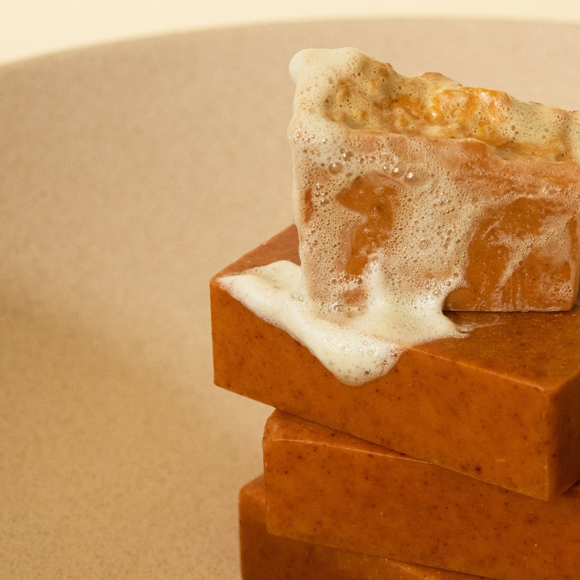 stack of clear bar soap with suds on a beige background 