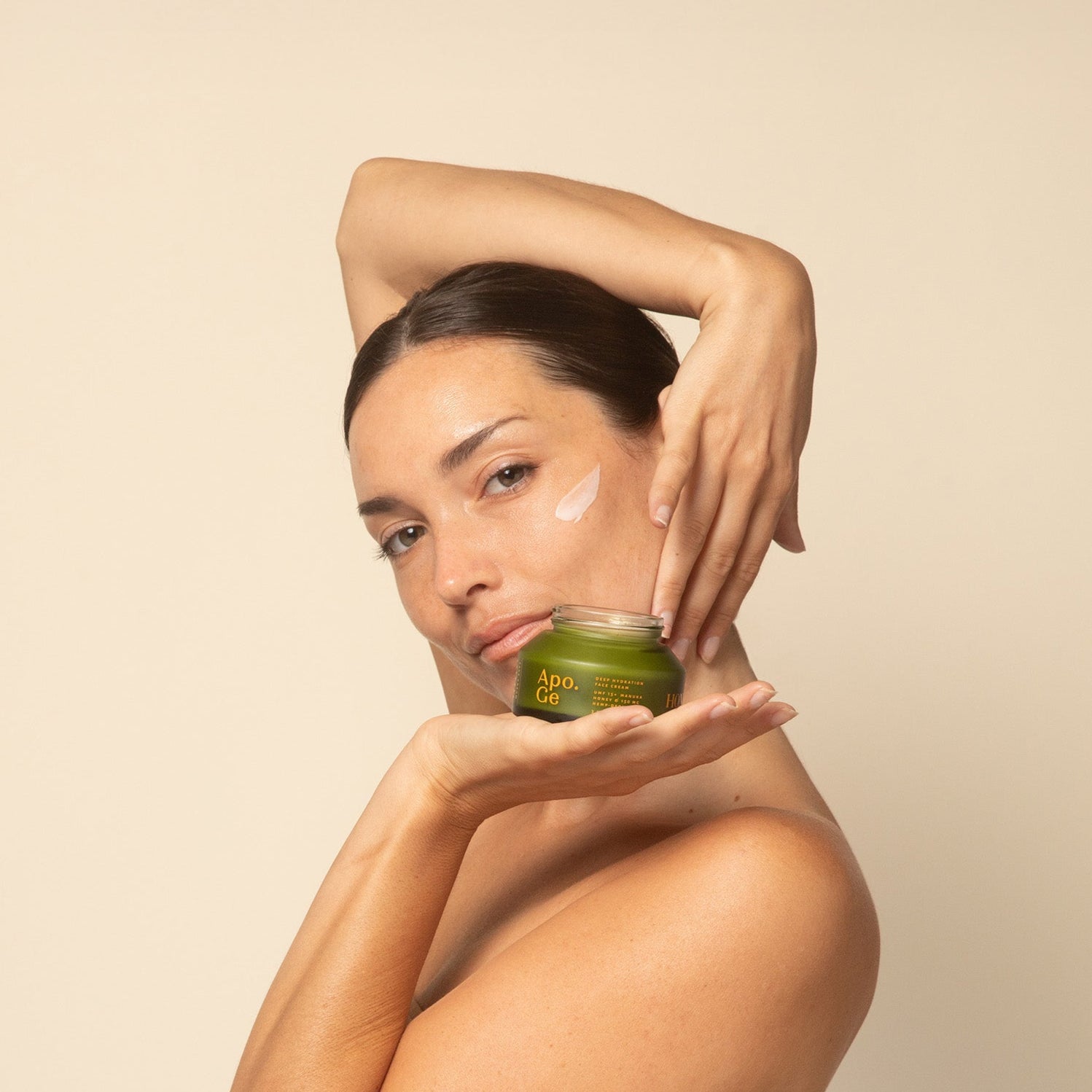 Woman applying apo ge manuka honey skincare deep hydration face cream to her face against a beige background