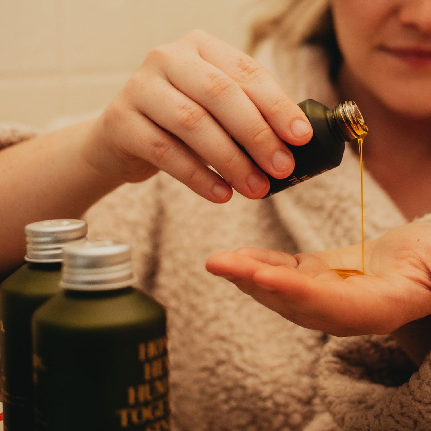 Person pouring apo ge manuka honey skincare renewing night elixer into their hand in a bathroom