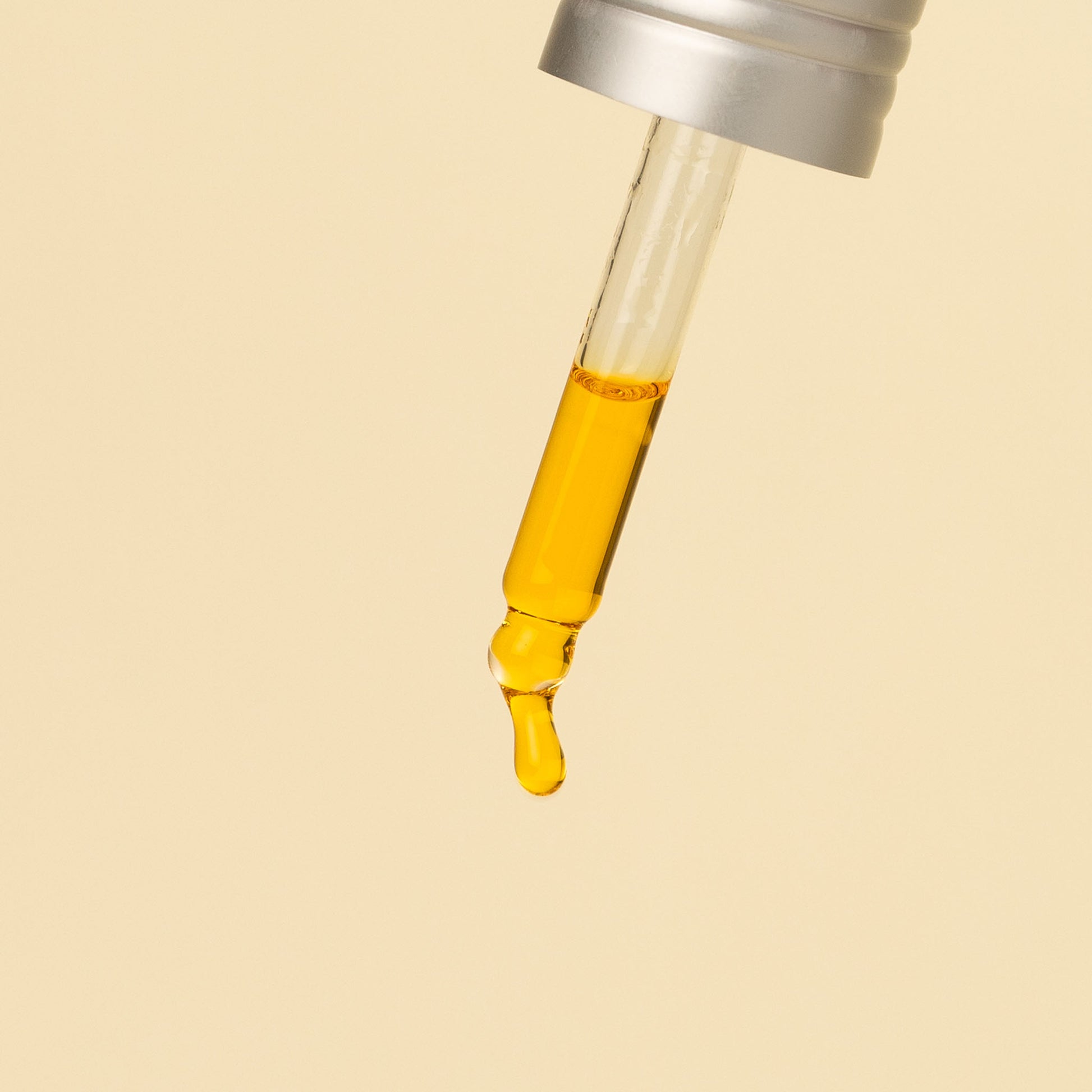 apo ge manuka honey skincare glass dropper filled with renewing night elixer on a beige background