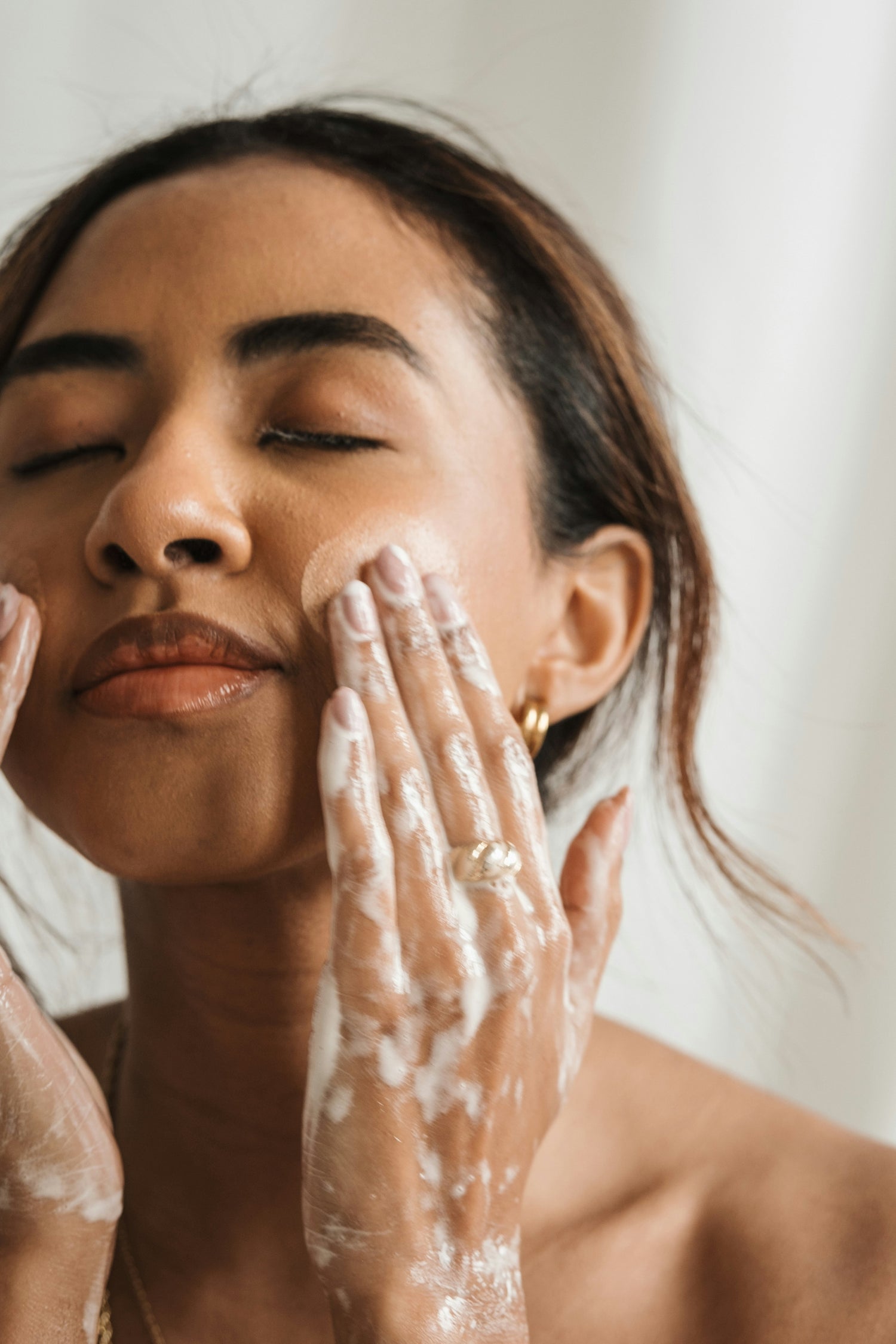 Woman washing her face with Apo.Ge Clarifying Milk Cleanse